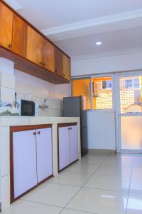 a kitchen with white cabinets and white tile floors at Appartement Cosy 3 bonapriso in Douala