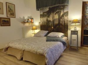 a bedroom with a bed with two lamps and a painting on the wall at Le Château de Roquebère in Condom