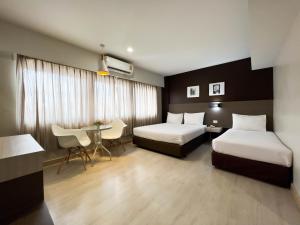 ein Hotelzimmer mit zwei Betten und einem Tisch in der Unterkunft Srivichai Hotel in Nakhon Ratchasima