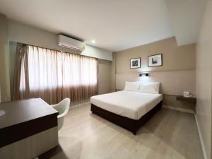 a hotel room with a bed and a desk at Srivichai Hotel in Nakhon Ratchasima