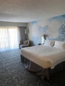 a hotel room with a large bed and a chair at Courtyard Boston Raynham in Raynham