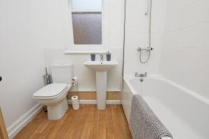 Baño blanco con aseo y lavamanos en Timeless Elegance 4-Bed Victorian Charm, en Leicester
