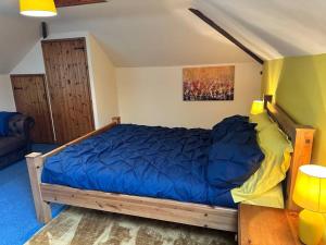 a bedroom with a wooden bed with a blue comforter at Stable Cottage in Germansweek