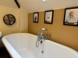 a bath tub in a bathroom with pictures on the wall at Stable Cottage in Germansweek