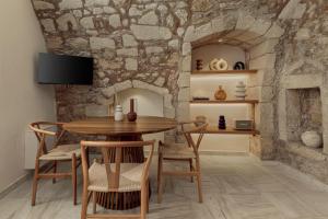 ein Esszimmer mit einem Tisch, Stühlen und einer Steinmauer in der Unterkunft Soleil boutique house with terrace in Rethymno