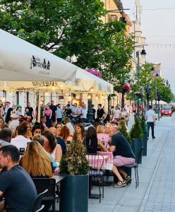 a group of people sitting at tables outside a restaurant at Hollywood Apartament Piotrkowska Klimat,Jakość,Styl in Łódź