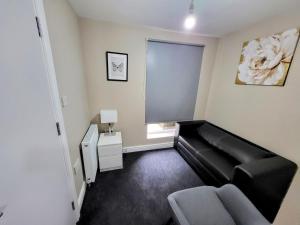 sala de estar con sofá negro y ventana en Stay Sleep Rest - NG2 en Nottingham