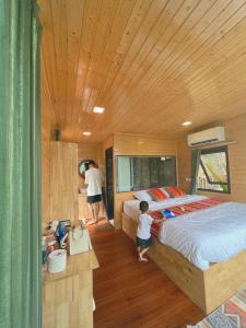 a little boy standing in a bedroom with a bed at Mường Lống Ecogarden 