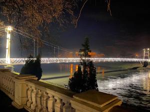 eine Brücke über einen Fluss in der Nacht mit Lichtern in der Unterkunft Apartman MiNa in Mataruška Banja