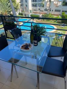 a glass table with a plate of food and two wine glasses at Sunylife in Albir