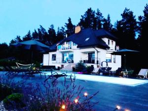 a large white house with a swimming pool at night at Saskia Dwór & Spa Willa z basenem in Podmacharce