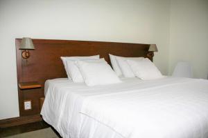 1 cama grande con sábanas y almohadas blancas en Casa do Largo - Açores, en Ponta Delgada