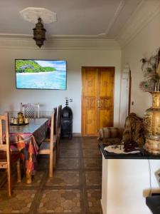 uma sala de jantar com uma mesa e uma televisão na parede em Lovely holiday Private villa with nature view +pool em Larache