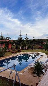 a large swimming pool with a wooden deck next to it at Lovely holiday Private villa with nature view +pool in Larache