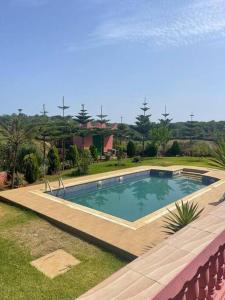 una piscina con una terraza de madera alrededor en Lovely holiday Private villa with nature view +pool en Larache