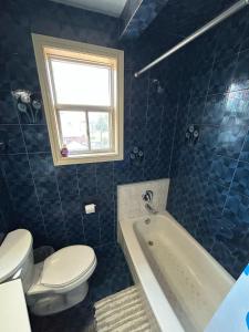 uma casa de banho em azulejos azuis com um WC e uma banheira em TORONTO Midtown Spot 1 em Toronto