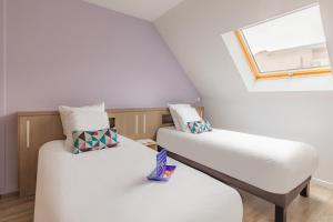 two beds in a room with a window at Appart'City Confort Pau Centre in Pau