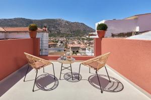 un patio con 2 sillas y una mesa en el balcón en Vin Dimora Suites, en Archanes