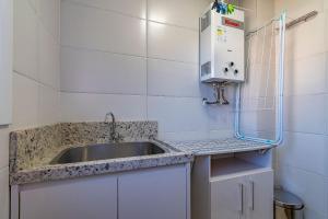 a kitchen with a sink and a microwave at Bem localizado - @stayhousetemporada in Canela +16 photos