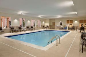 - une piscine dans une chambre d'hôtel dotée de tables et de chaises dans l'établissement Homewood Suites by Hilton Kalamazoo-Portage, à Kalamazoo