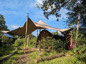 uma tenda em frente a uma cabana num campo em Luxe glamping "De Steenuil" met sauna em Volkel