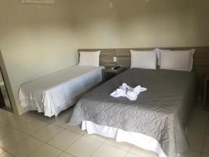 Habitación de hotel con 2 camas con flores blancas. en Hotel Sabrina en Guanambi