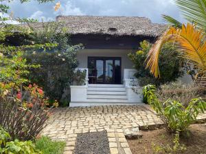 a small house with a thatch roof at VILLABLANCA in Nosy Be