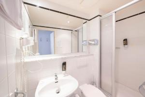 Hotel Astoria Stuttgart City في شتوتغارت: حمام أبيض مع حوض ودش