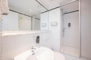 a white bathroom with a sink and a shower at Hotel Astoria Stuttgart City in Stuttgart