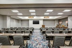 a conference room with tables and chairs and a screen at Hilton Garden Inn Boston Waltham in Waltham