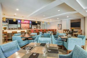 a restaurant with blue chairs and tables and a bar at Hilton Garden Inn Boston Waltham in Waltham