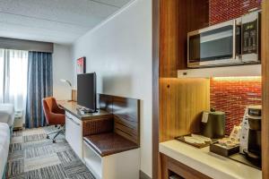 Habitación de hotel con cama y escritorio con TV. en Hilton Garden Inn Boston Waltham en Waltham