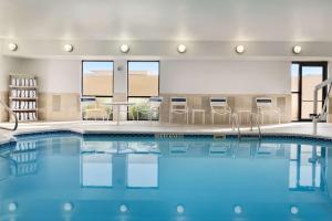 uma piscina com cadeiras e mesas num quarto de hotel em Hampton Inn Battle Creek em Battle Creek