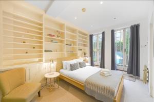 ロンドンにあるCentral 2Bed Apartment near Barbican & Farringdon FREE WIFI by City Stay Aparts Londonのベッドルーム1室(木製の棚、ベッド1台、椅子付)
