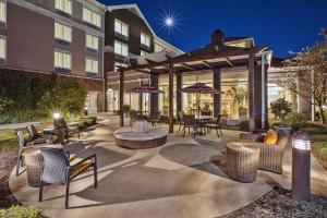 un patio al aire libre con sillas, mesas y sombrillas en Hilton Garden Inn Akron-Canton Airport, en North Canton