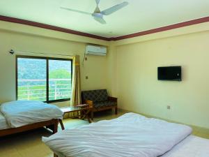 a bedroom with two beds and a tv on the wall at Kashmir Heaven Guest House in Muzaffarabad