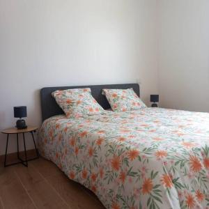 a bedroom with a bed with a floral comforter and a table at Gîte pour 8 personnes in Frespech