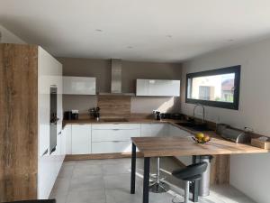 cocina con armarios blancos y mesa de madera en Superbe villa avec piscine proche de belfort, en Meroux