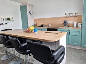 a kitchen with blue cabinets and a island with black chairs at Teach Aindí (newly renovated cottage) in Belmullet