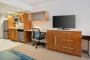 ein Büro mit einem Schreibtisch, einem TV und einem Stuhl in der Unterkunft Home2 Suites Charlotte I-77 South in Charlotte