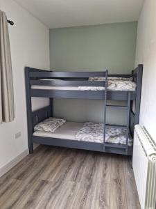 two bunk beds in a room with a wooden floor at Teach Aindí (newly renovated cottage) in Belmullet