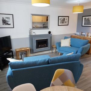 a living room with two blue couches and a fireplace at Darcey's Apartment in Bowness-on-Windermere