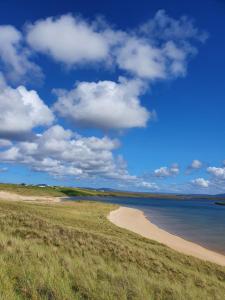 a beach with the ocean and a blue sky and clouds at Teach Aindí (newly renovated cottage) in Belmullet