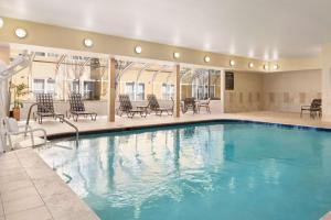 a pool in a hotel with chairs and tables at Homewood Suites by Hilton Columbus-Hilliard in Hilliard