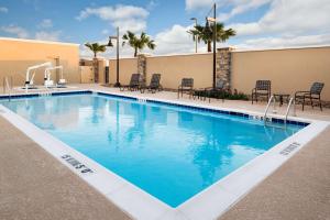 a swimming pool at a hotel with tables and chairs at Hampton Inn & Suites Corpus Christi, TX in Corpus Christi