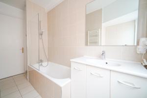 ein weißes Bad mit einem Waschbecken und einer Dusche in der Unterkunft Apartment next to Louis Vuitton Fondation in Neuilly-sur-Seine