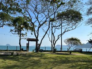 a park with trees and a bench and the ocean at Summit Beach Hotel Boiçucanga in Boicucanga