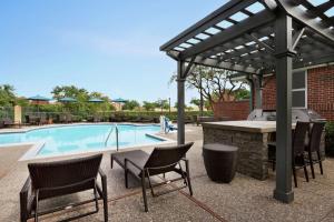 un patio con parrilla, mesa y sillas junto a la piscina en Homewood Suites Dallas-Addison en Addison