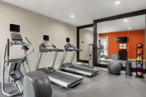 un gimnasio con tres máquinas de correr y un espejo en Homewood Suites Dallas-Addison en Addison