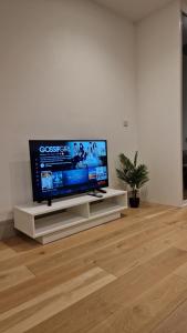 a flat screen tv sitting on a white stand in a living room at London Stadium Apartment in London